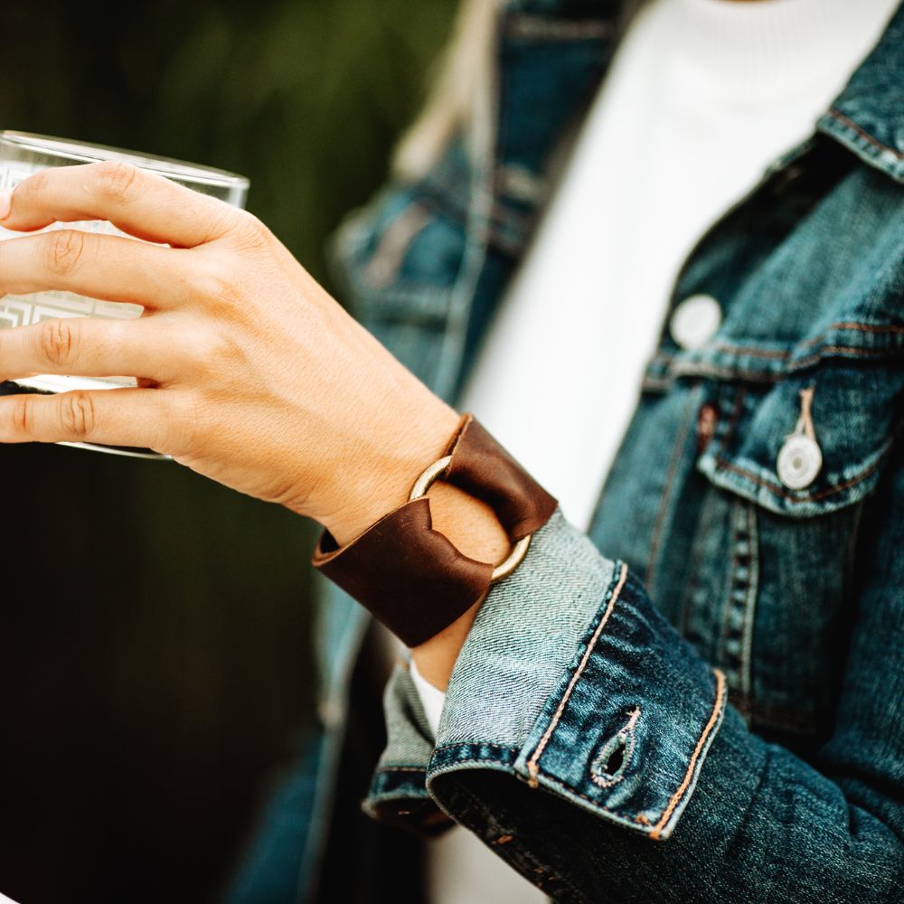 Woman wearing silver and white rustic leather cuff bracelet while playing guitar
