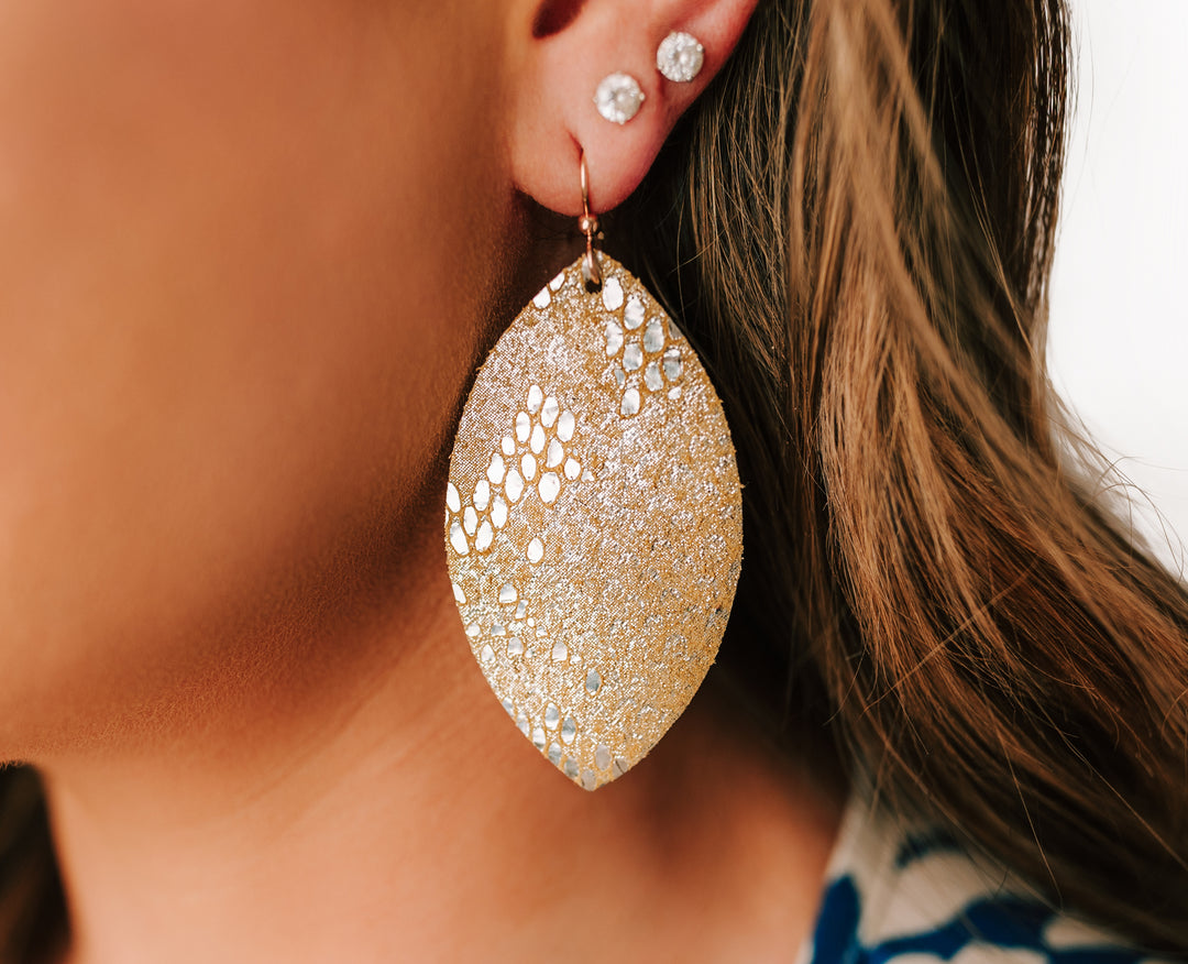 Woman wearing gold and silver speckled leather earrings